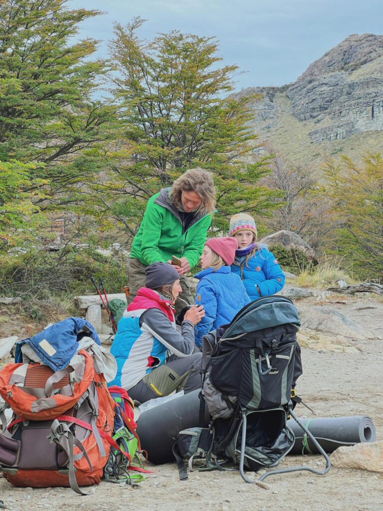 A family of four taking a break during a hiking adventure in a scenic mountain area.