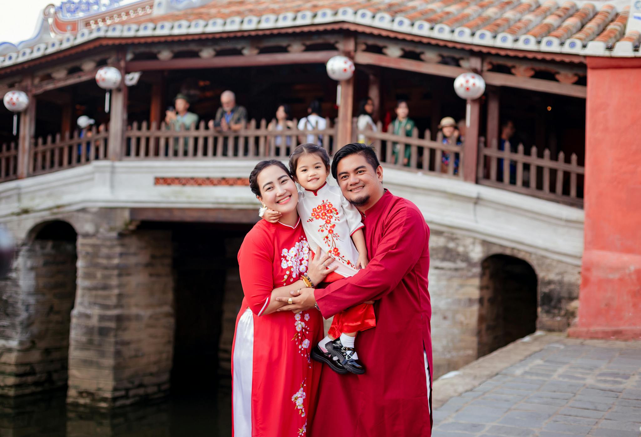 Happy family in traditional attire posing at Hội An's iconic Japanese Bridge.
